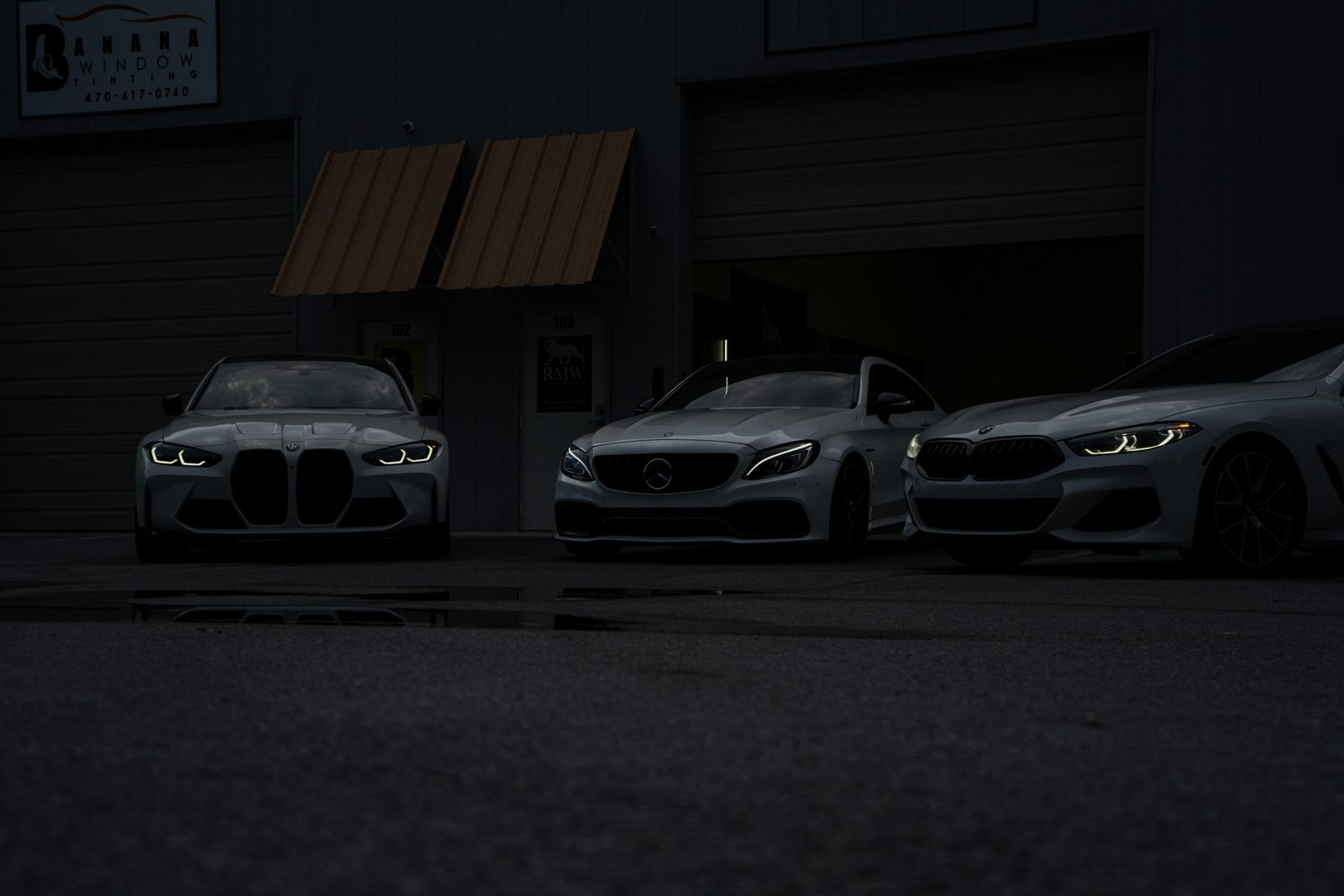 Three cars parked in front of a building at night