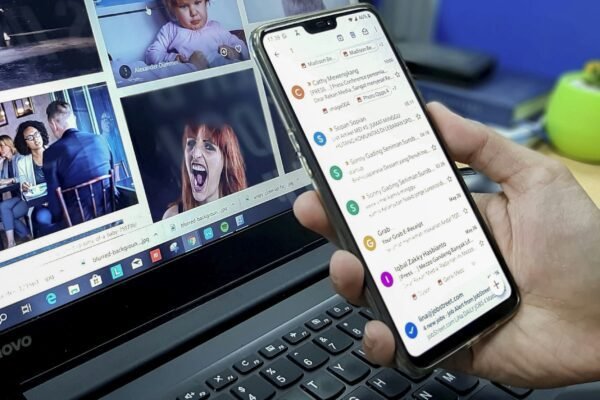 person using smartphone and laptop computer
