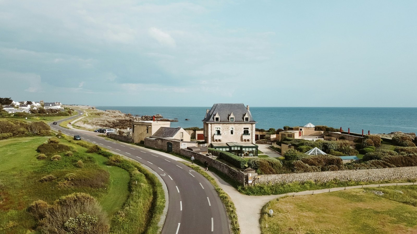 a house on the side of a road next to the ocean