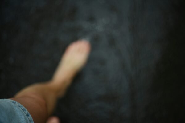 A bare foot on dark, wet ground.